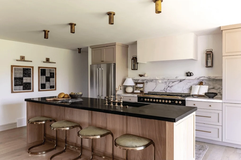 Warm kitchen with stone island and brass stools