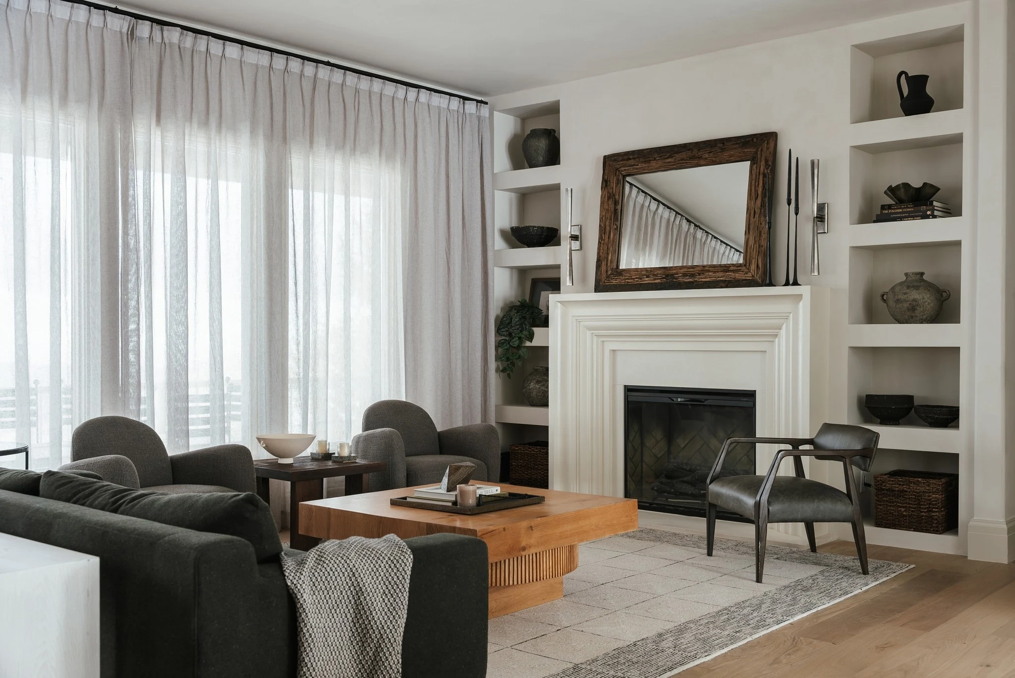 Living room with fireplace, built-in shelves, and full-height curtains